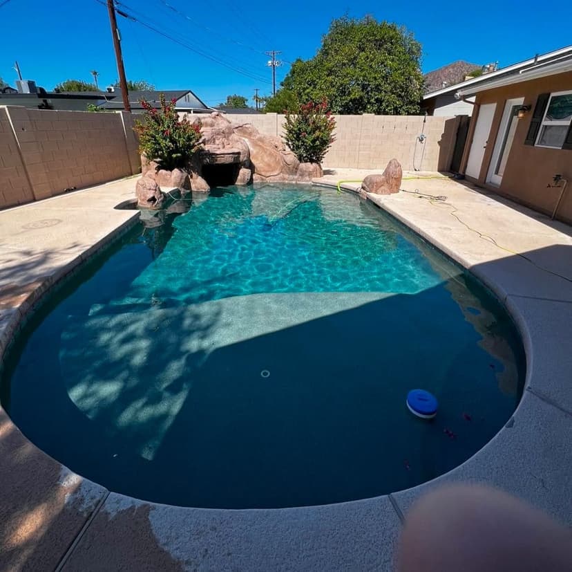 Freeform backyard pool with a rock grotto and waterfall feature