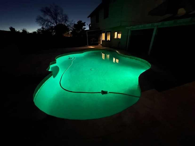 Freeform backyard pool illuminated with green LED light at night